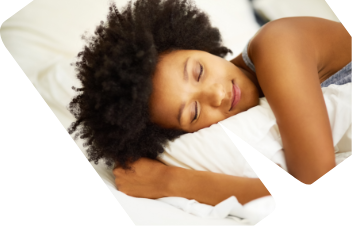 Eine Frau liegt schlafend in einem Bett mit weißer Bettwäsche.