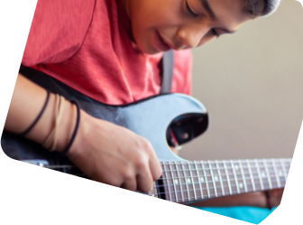Ein junge spielt auf einer schwarzen E-Gitarre. 