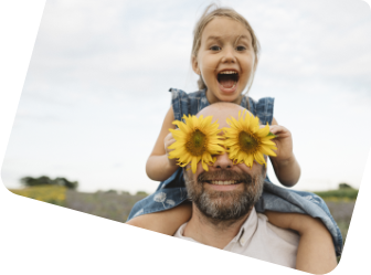 Ein Mädchen sitzt auf den Schultern eines bärtigen Mannes mit Blumen vor den Augen.