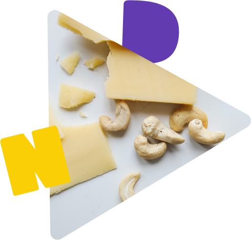 Käse und Cashewkerne auf weißen Grund verteilt.