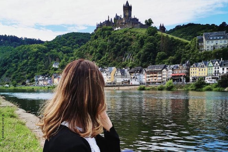 Aylin schaut über einen Fluß hinweg auf eine kleine Stadt. 