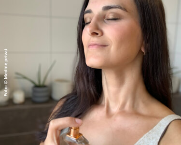 Medine besprüht ihren Hals mit einem Parfum.