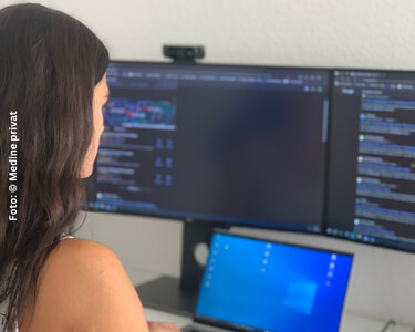 Medine schaut auf einen Computerbildschirm.