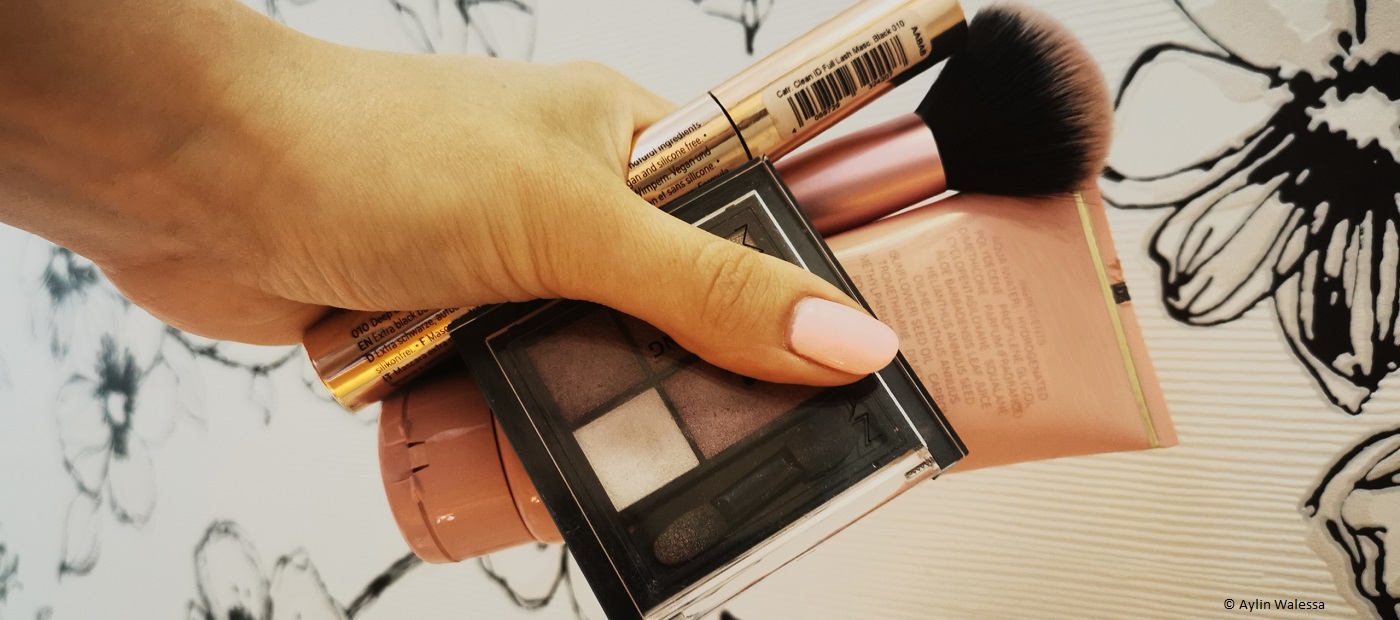 Eine Hand hält verschiedene Make-Up Artikel. 