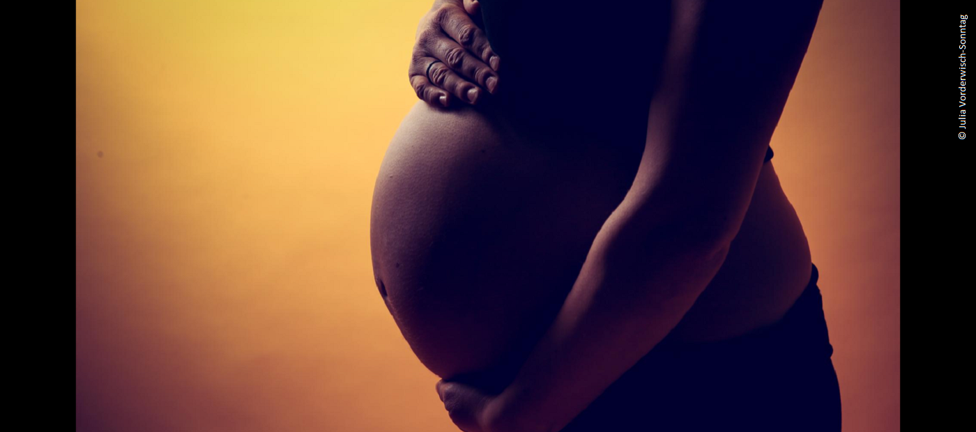 Der Bauch einer schwangeren Frau von der Seite. 