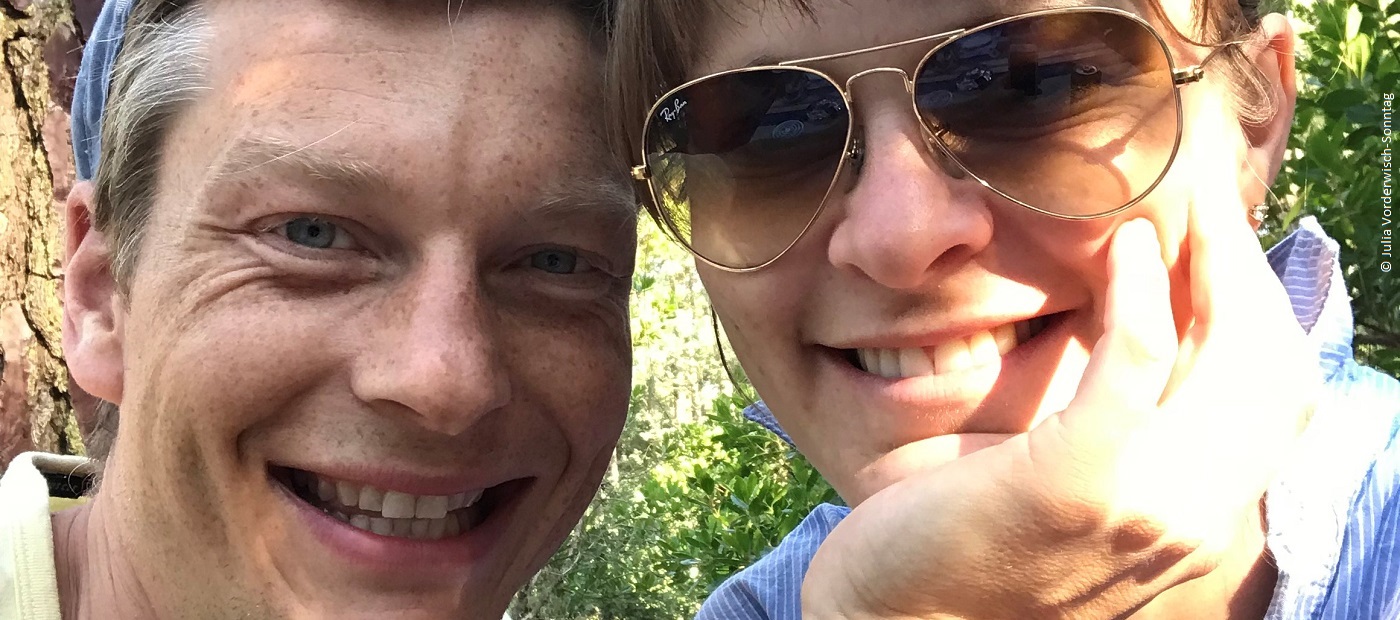 Ein Bild von Julia, wie sie zusammen mit einem Mann in die Kamera lacht.
