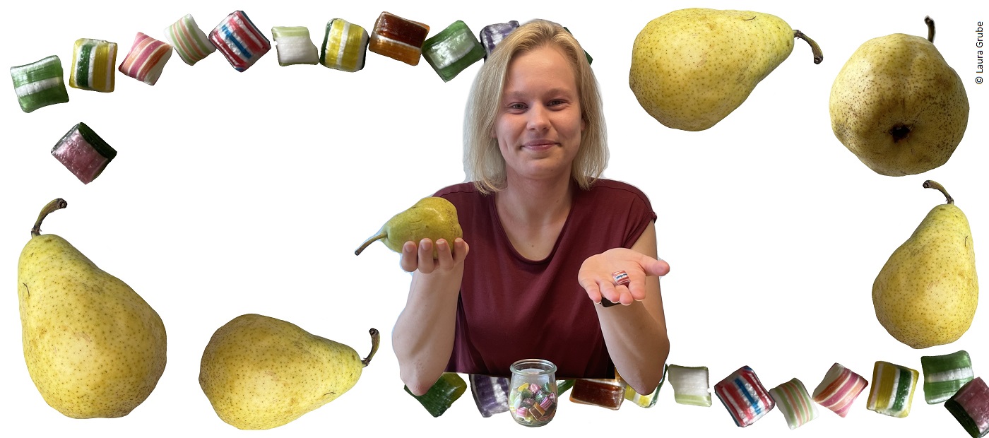 Laura hält eine Birne in der rechten Hand und ein Weingummi in der linken Hand. 