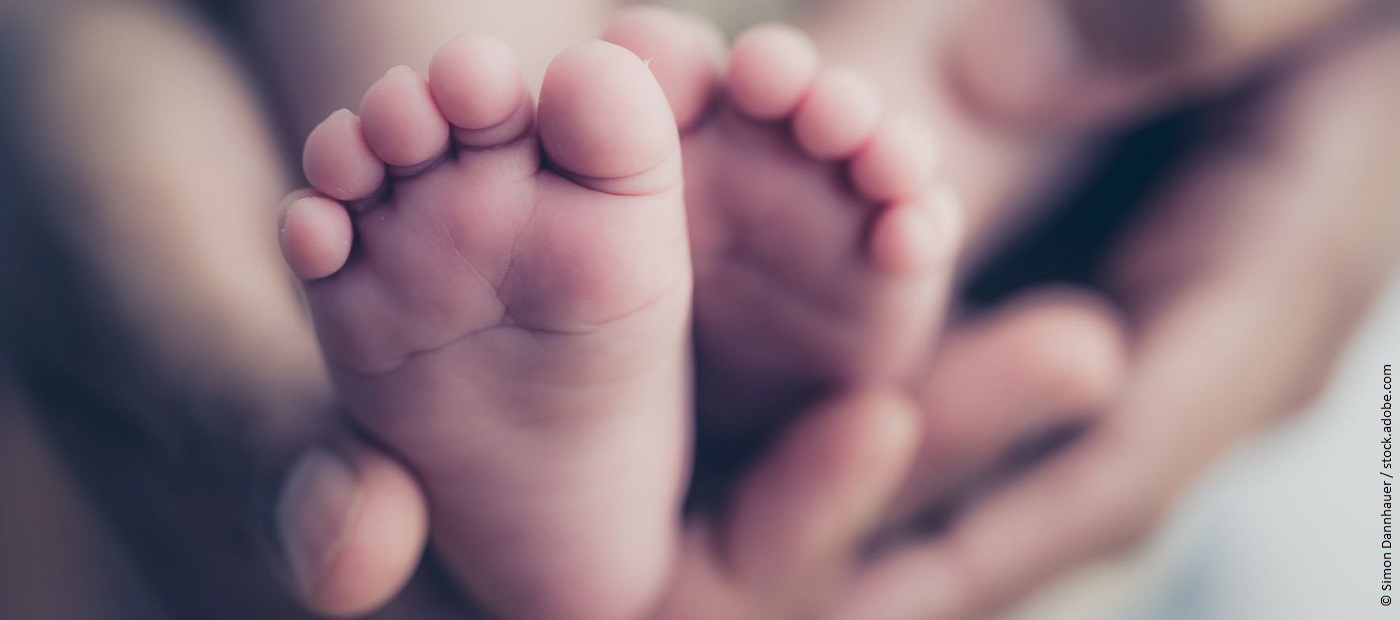 Nackte Babyfüße werden in die Kamera gehalten. 