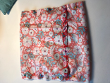 Eine Tasche auf aus rotem Stoff mit bunten Blumen. 