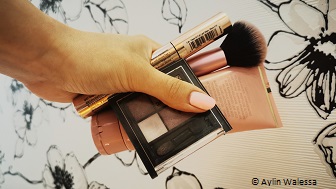 Eine Hand hält verschiedene Make-up Artikel in der Hand.