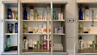 Ein geöffneter Badezimmerspiegelschrank mit diversen Cremes und Hygieneartikeln.  