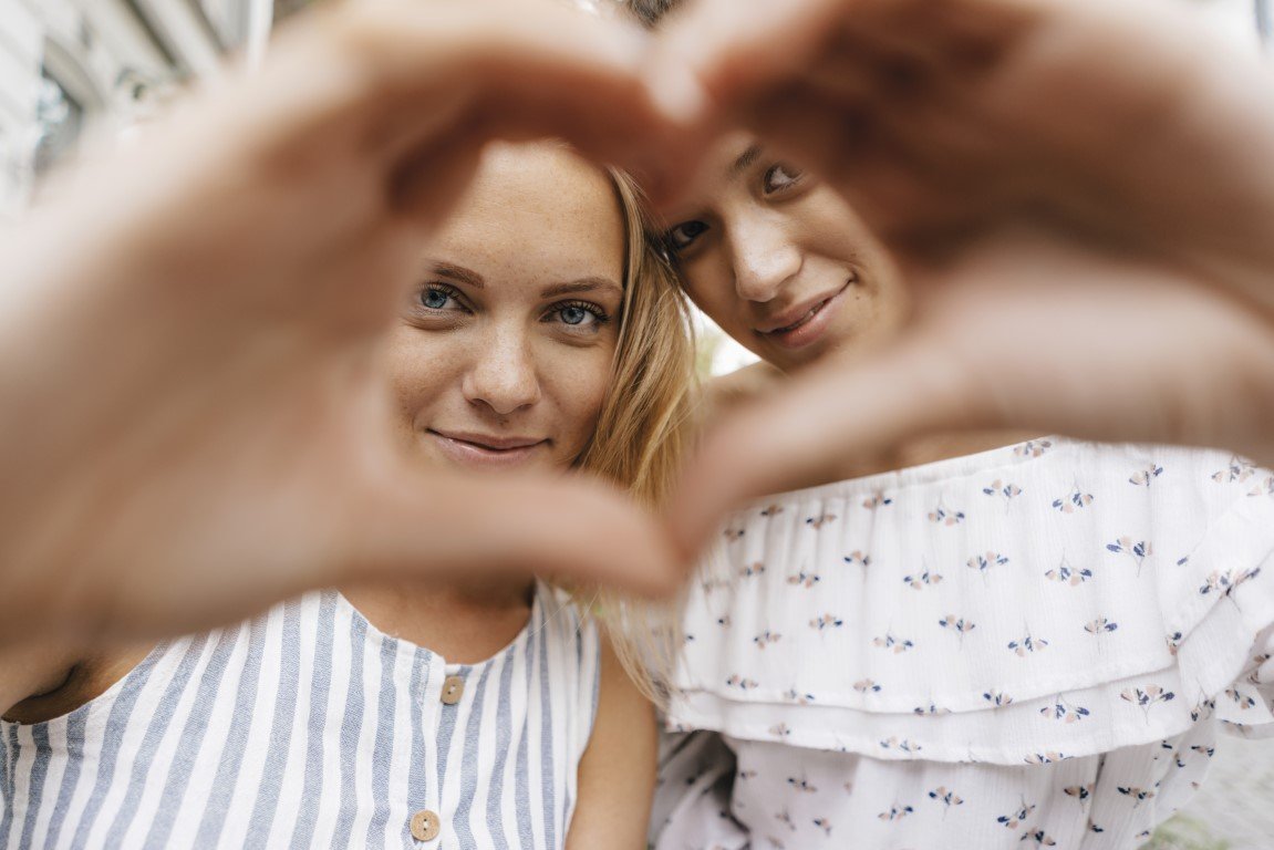 Zwei junge Frauen bilden mit ihren Händen gemeinsam ein Herz