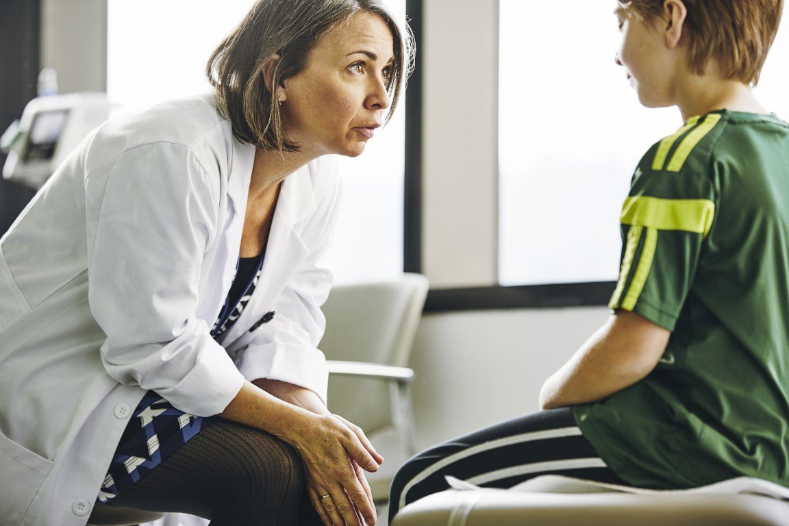 Eine Ärztin spricht mit einem kleinen Jungen im Behandlungsraum.