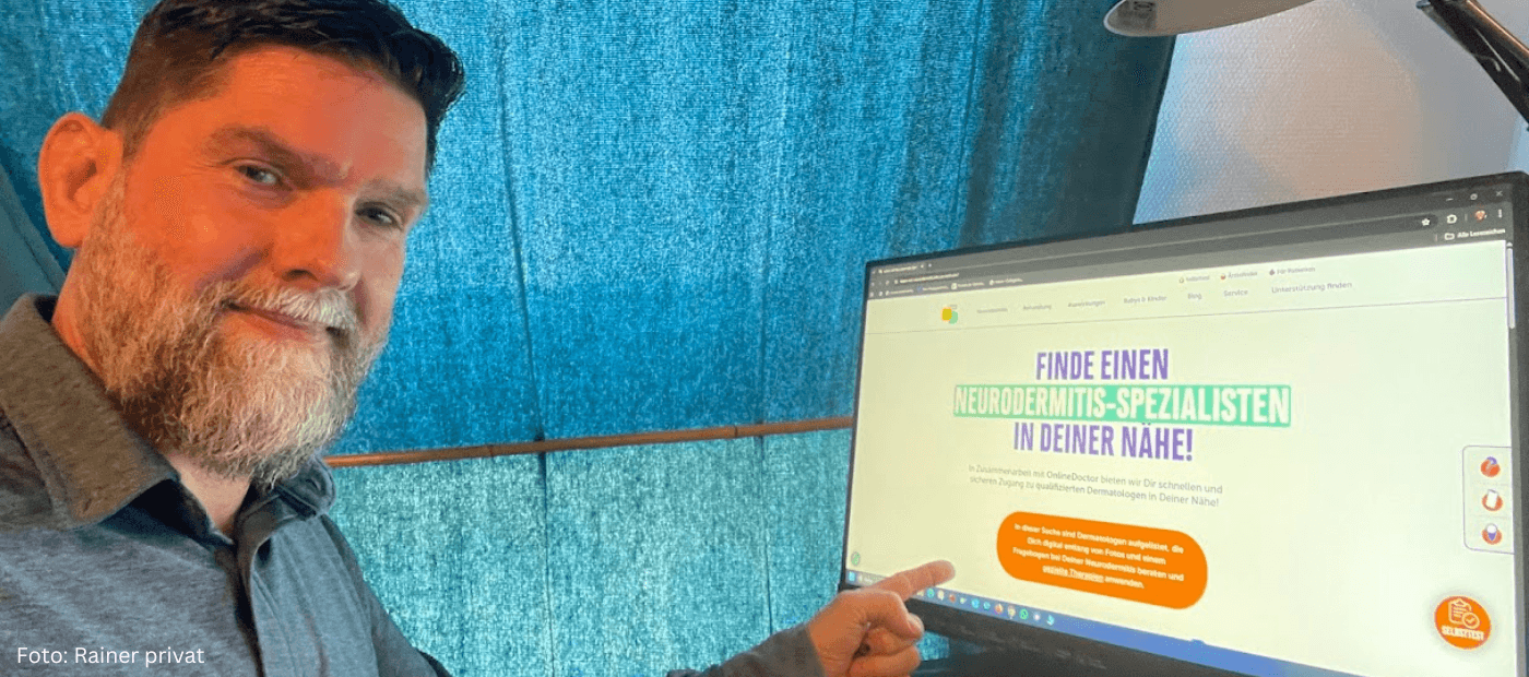 Mann zeigt auf Monitor mit Website zu Neurodermitis-Expertenfinder