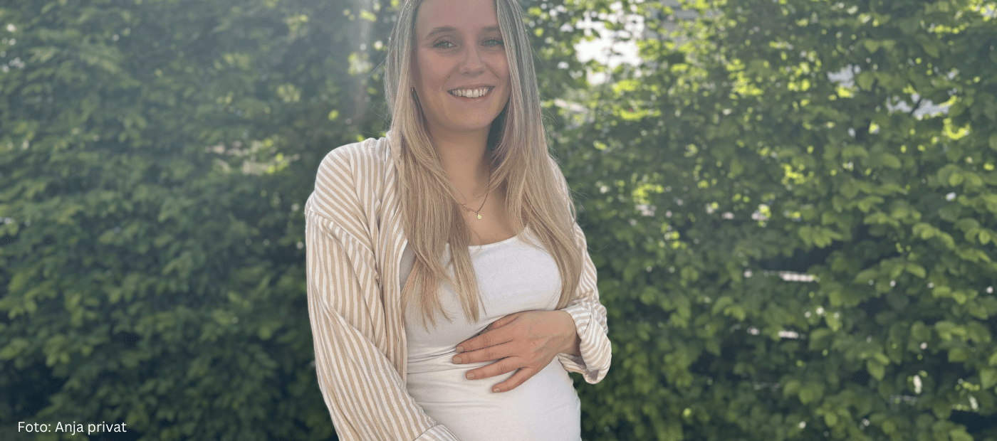 Schwangere Frau steht im Garten und hält ihren Bauch