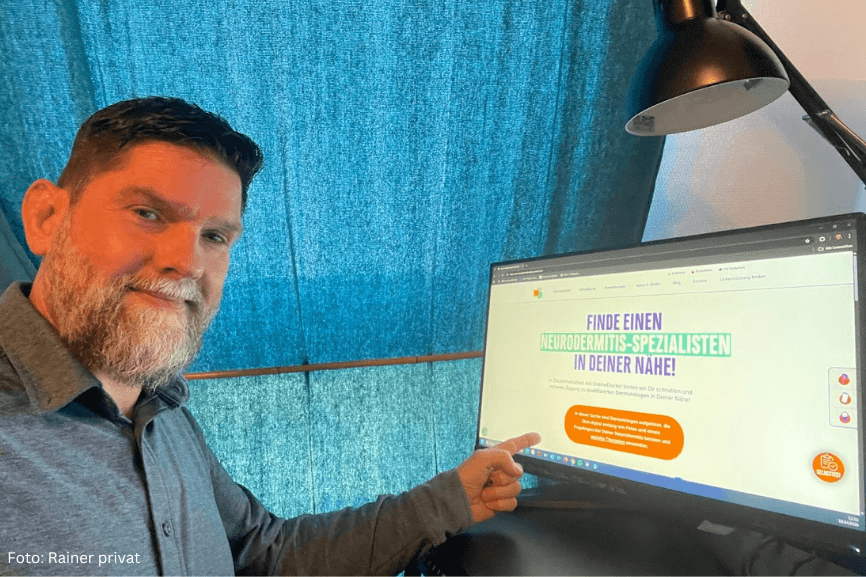 Mann zeigt auf Monitor mit Website zu Neurodermitis-Expertenfinder