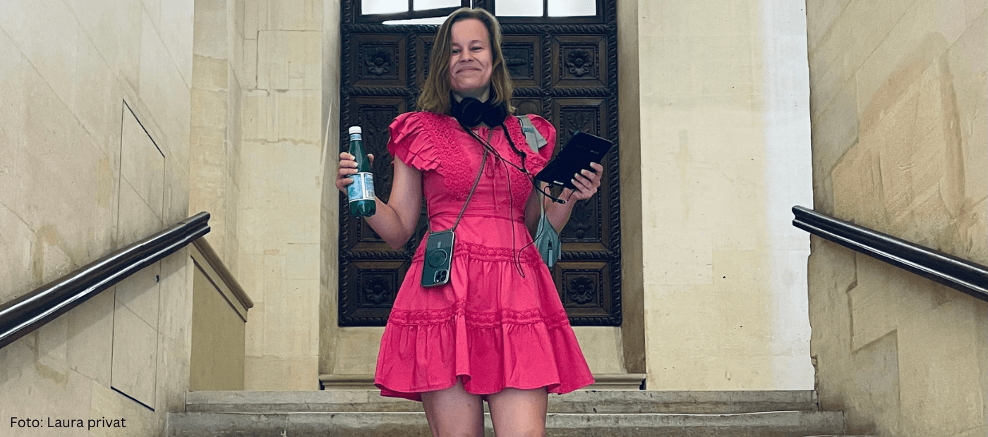 Frau im pinken Kleid auf einer Treppe mit Smartphone und Flasche.