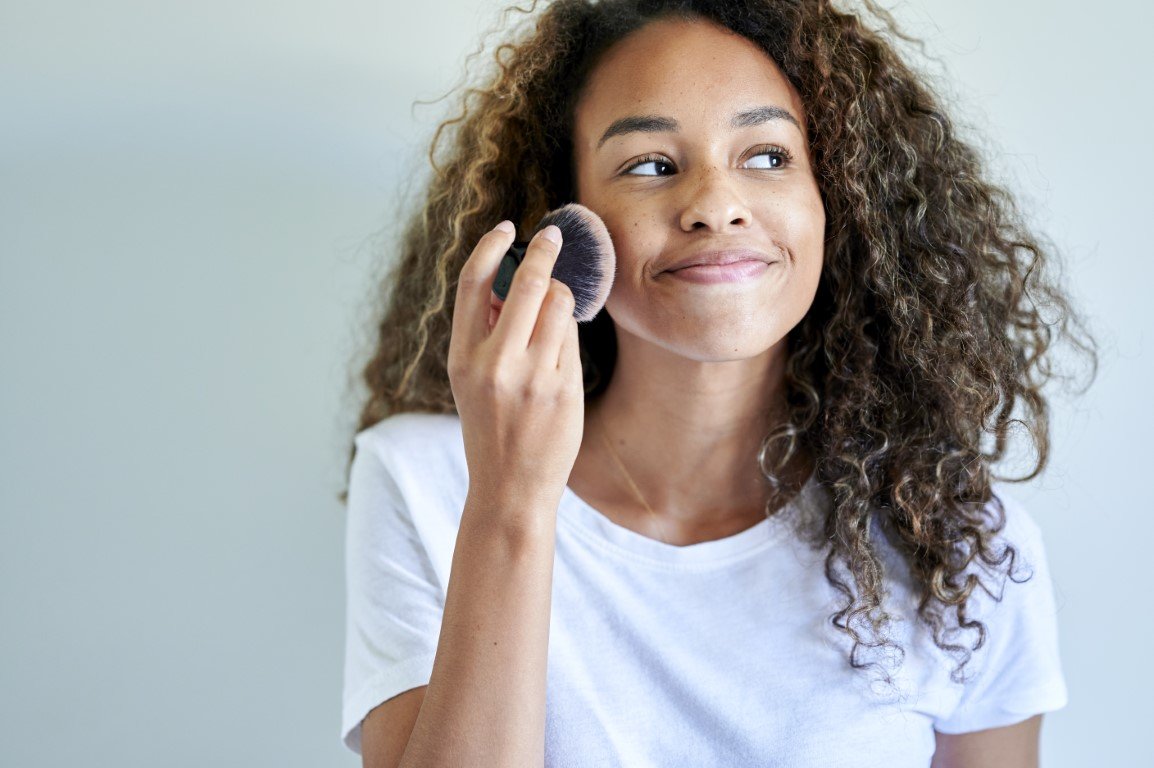 Frau trägt Make-up im Gesicht auf