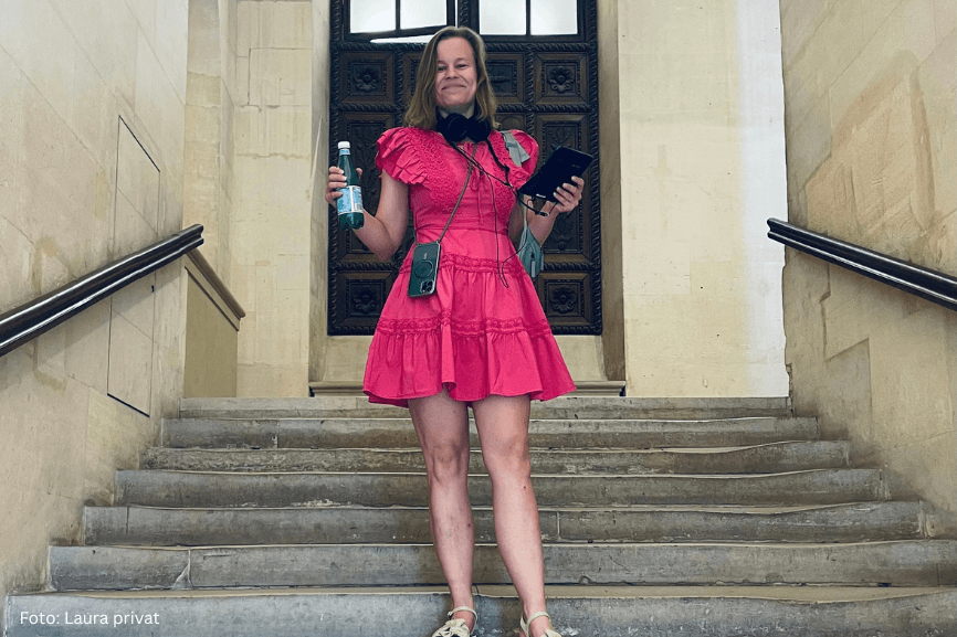 Frau im pinken Kleid auf einer Treppe mit Smartphone und Flasche.