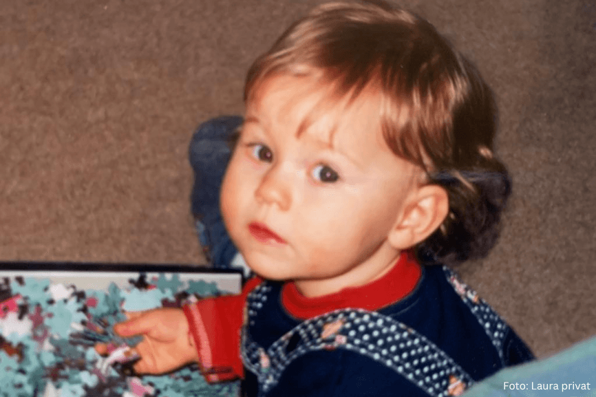 Laura als Kleinkind mit leichten Rötungen an den Wangen beim Puzzeln