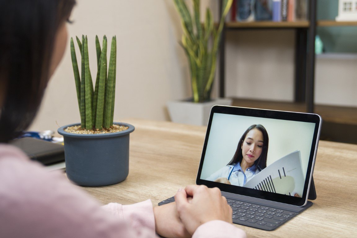 Ein Laptop, auf dem Bildschirm ist eine junge Ärtztin zu sehen