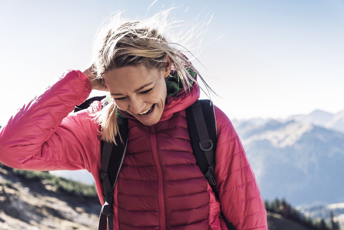 Eine lächelnde junge Frau bei Wind und Wetter in der Natur