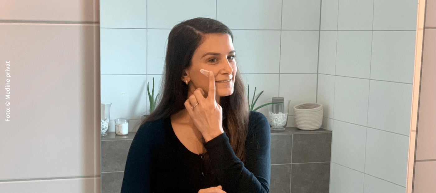 Medine cremt sich ihr Gesicht vor dem Badspiegel ein, um Ihre Neurodermitis zu pflegen