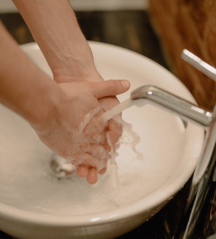 Person wäscht sich die Hände am Waschbecken