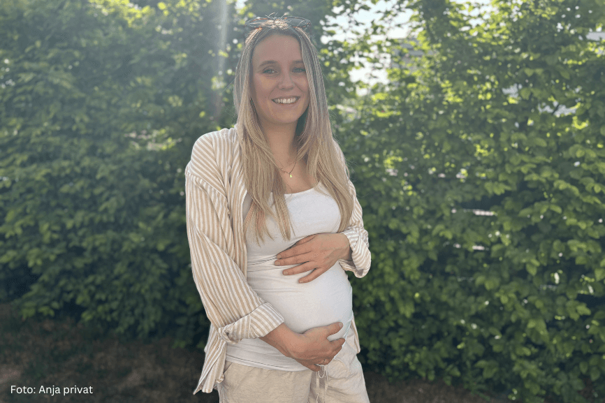 Schwangere Frau steht im Garten und hält ihren Bauch