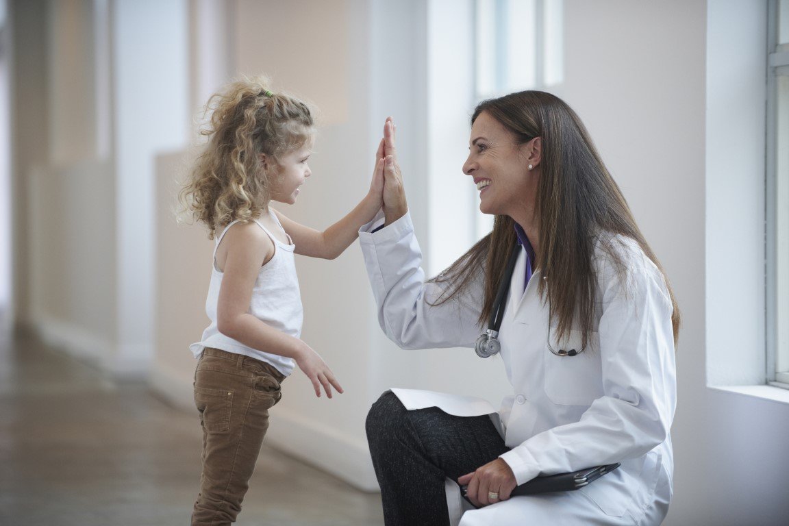 Eine Ärztin klatscht mit einem kleinen Mädchen ab.