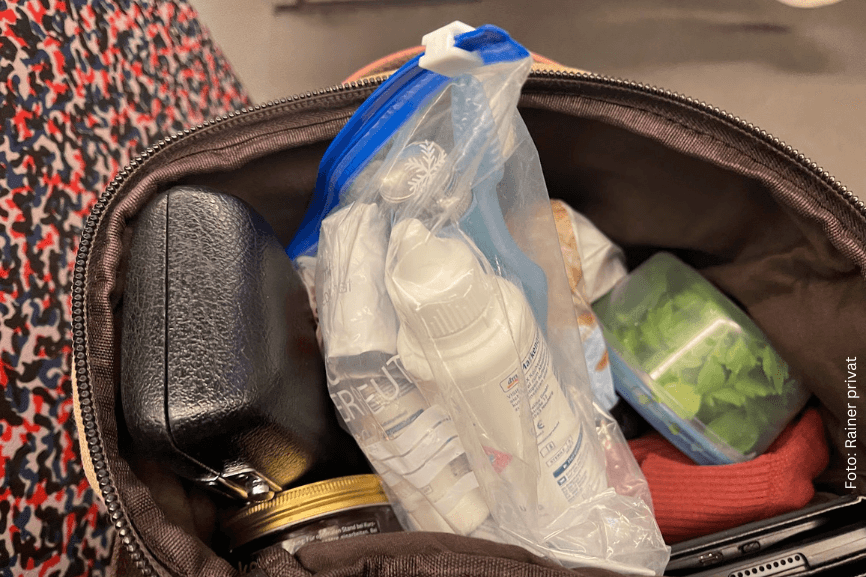 Offene Tasche mit Reiseutensilien, darunter Kosmetiktasche und Hygieneartikel