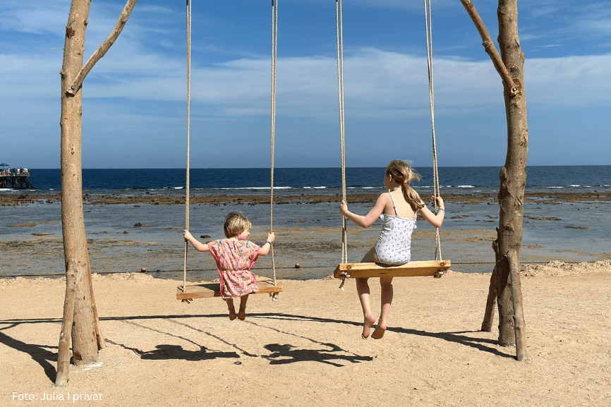 Zwei Kinder auf zwei Schaukeln am Strand – Julia berichtet in ihrem Erfahrungsbericht von ihrem Familienalltag mit Neurodermitis