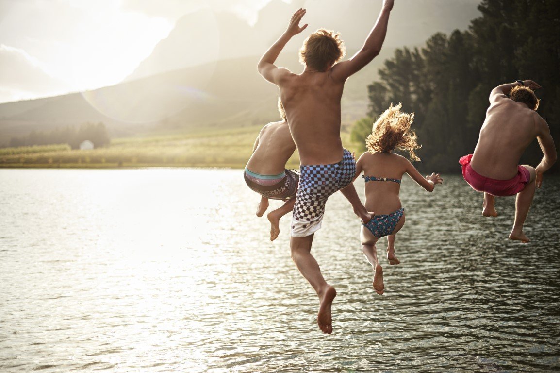 Eine Gruppe von Jugendlichen springt in einen See