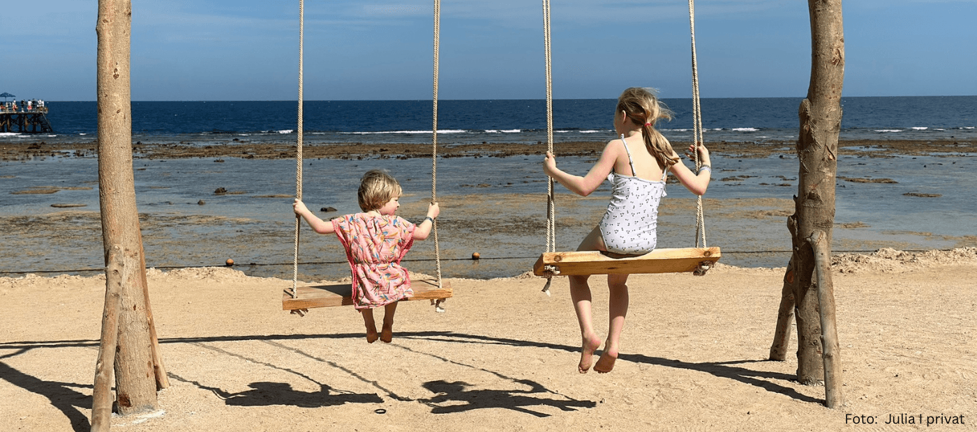 Zwei Kinder auf zwei Schaukeln am Strand – Julia berichtet in ihrem Erfahrungsbericht von ihrem Familienalltag mit Neurodermitis