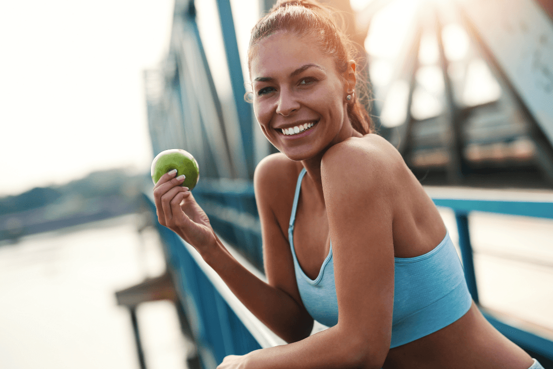 Junge Frau auf einer Brücke mit einem Apfel in der Hand.